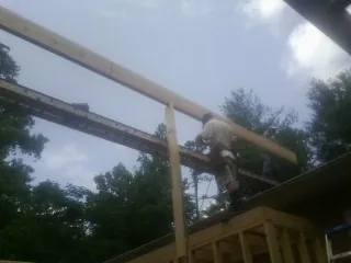 Carpenter setting a ridge beam over a new addition frame — Ice Dam Removal by Roofing Brothers in Kesley