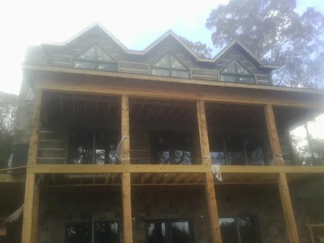 Dormers and porch framing on a large log home under construction — Roof Coating work by our crew in Kesley