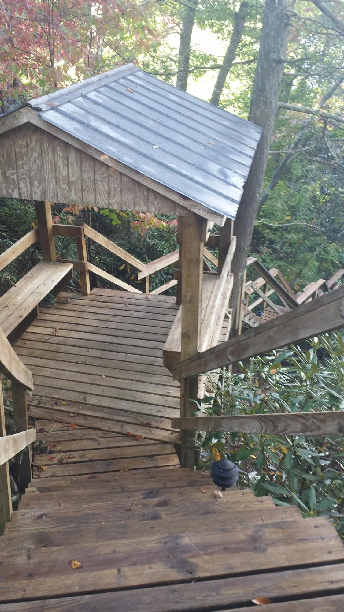 Metal roofed shelter over wooden steps on a wooded walkway — Skylight Repair & Installation work by our crew in Kesley